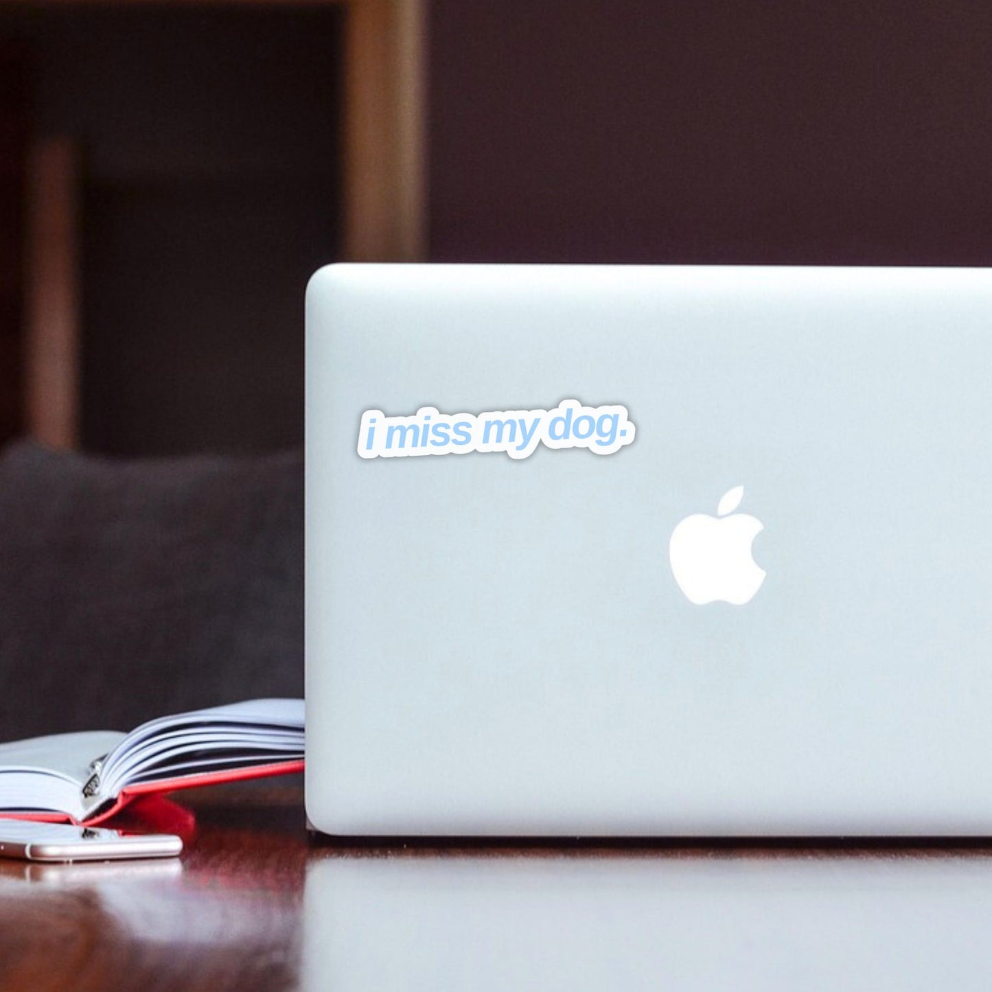 White laptop with 'i miss my dog.' sticker in light blue font