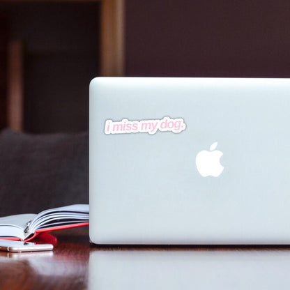 White laptop with 'i miss my dog.' sticker in light pink font